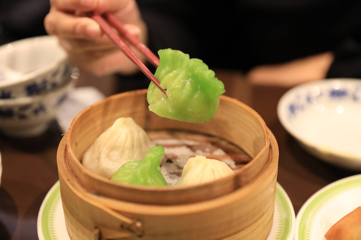 中華街　慶茶慶重：蒸籠に入った小籠包と箸で持ち上げられた小籠包