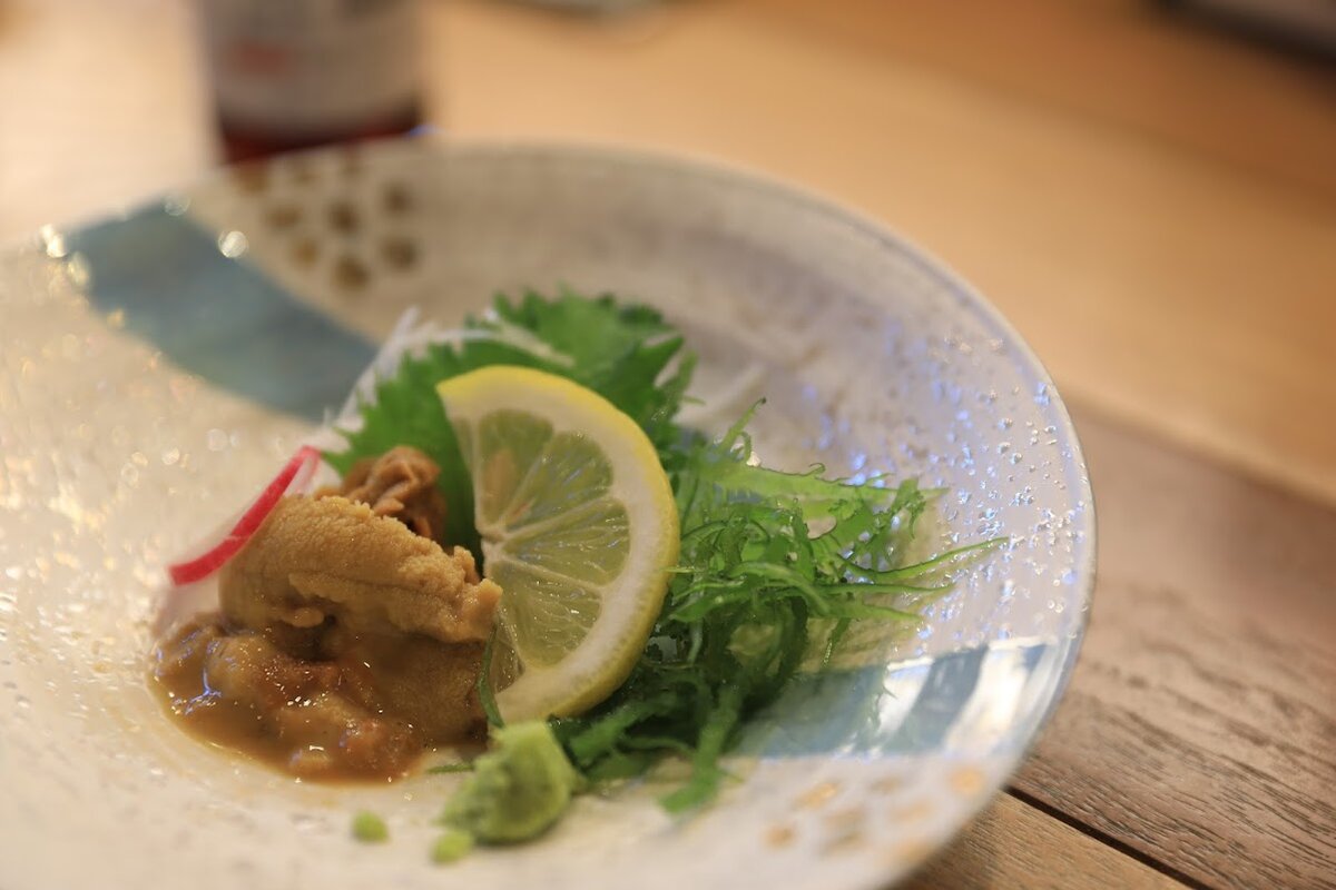 OZIO：白い建物の店舗外観。店名はOZIO。人が一人地面を清掃している。