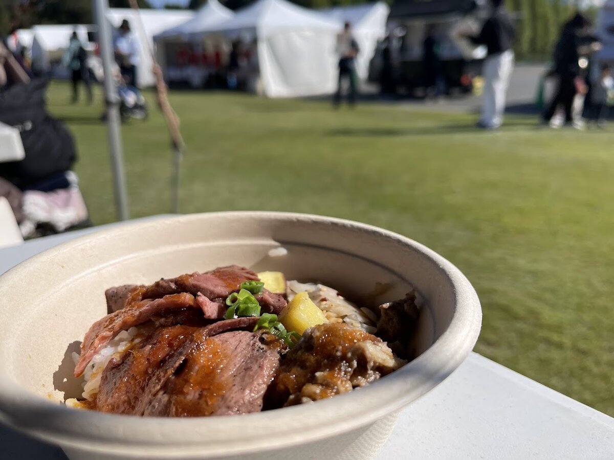 新宿御苑イベント:ローストビーフ丼と背景にテントや人々ジャージー牛のロース...