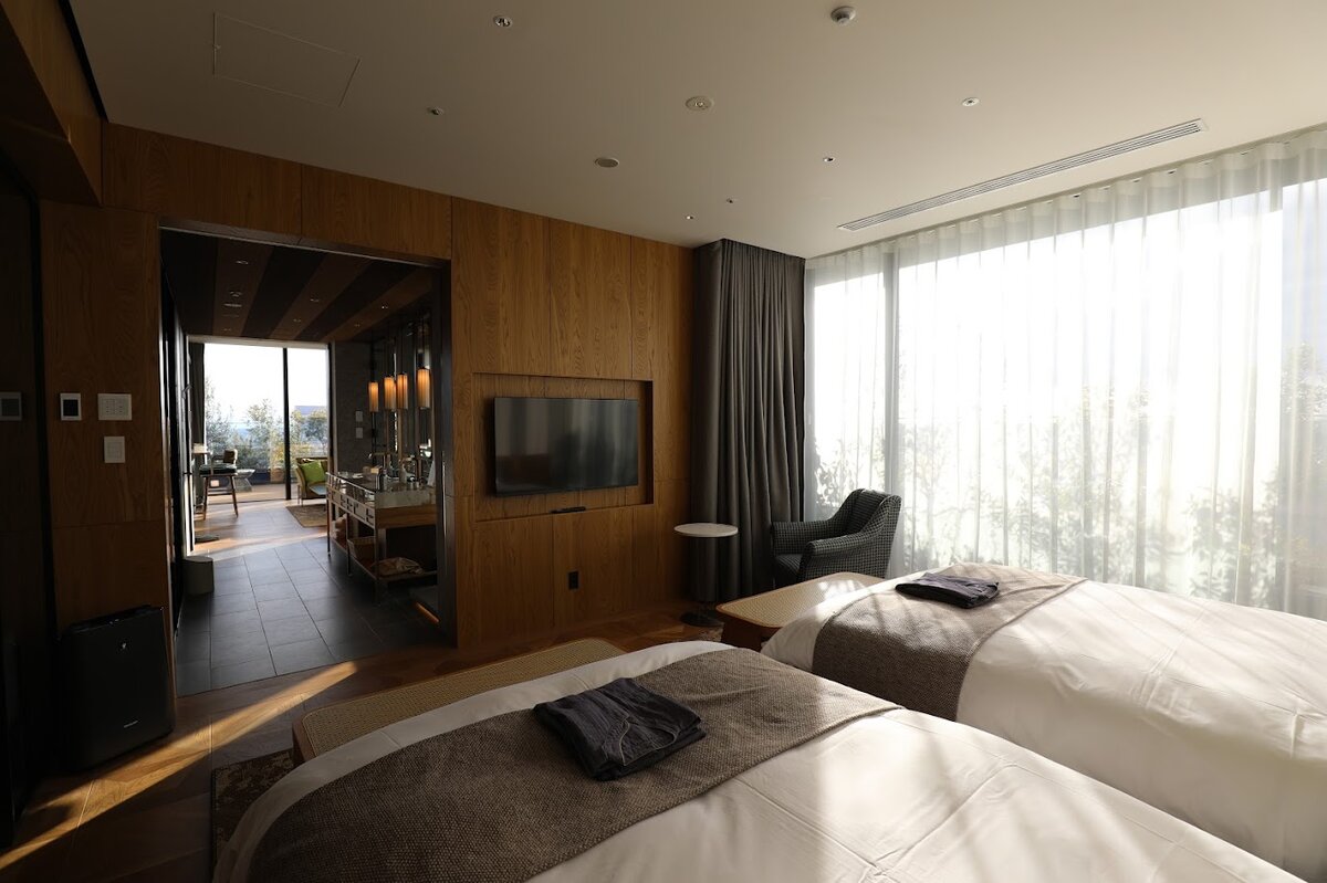 GREENITY IWATA：ツインベッドルームと椅子、窓の外には風景