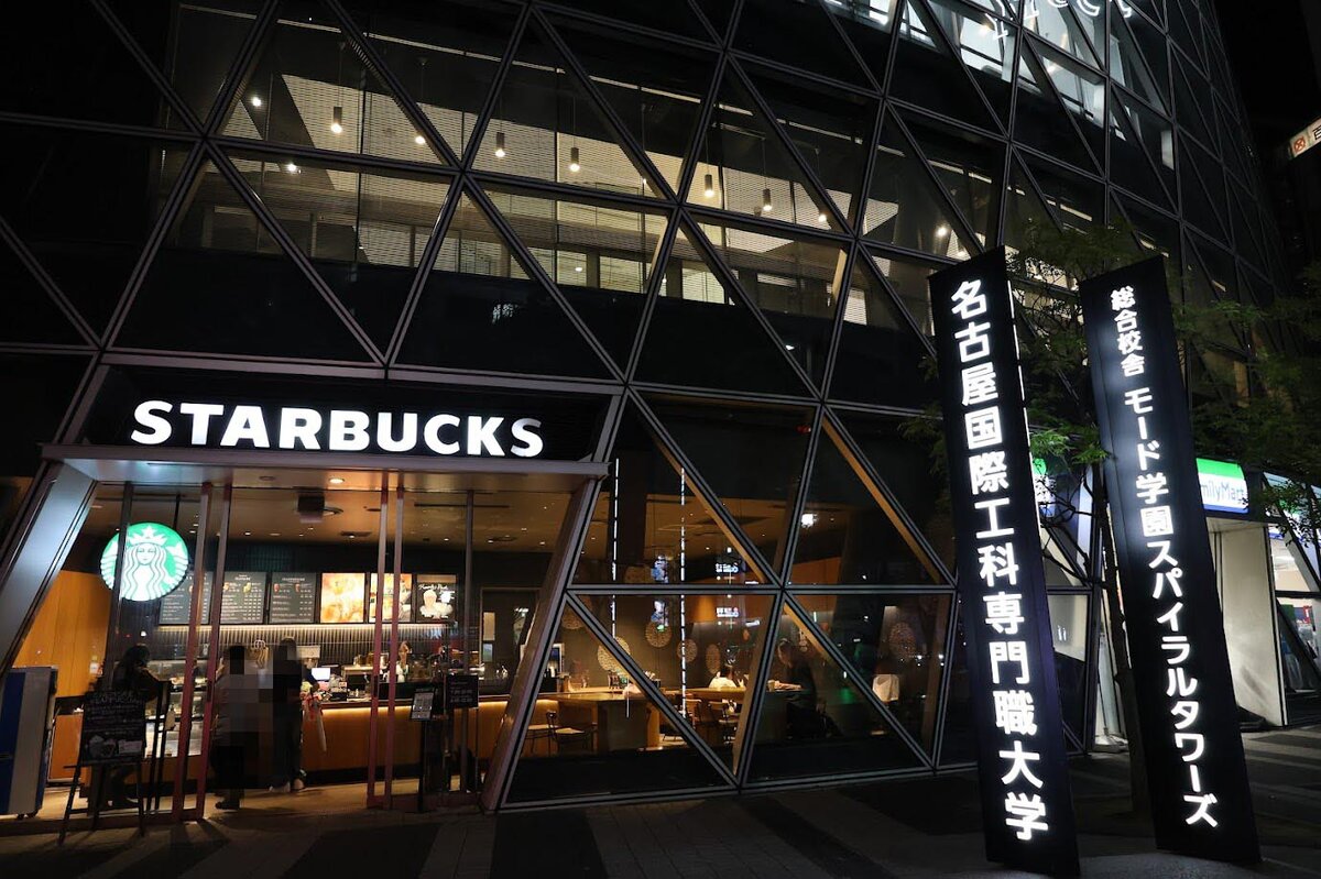スターバックス コーヒー 名古屋スパイラルタワーズ店：スターバックスの店舗外観。向かいには学校の看板がある。