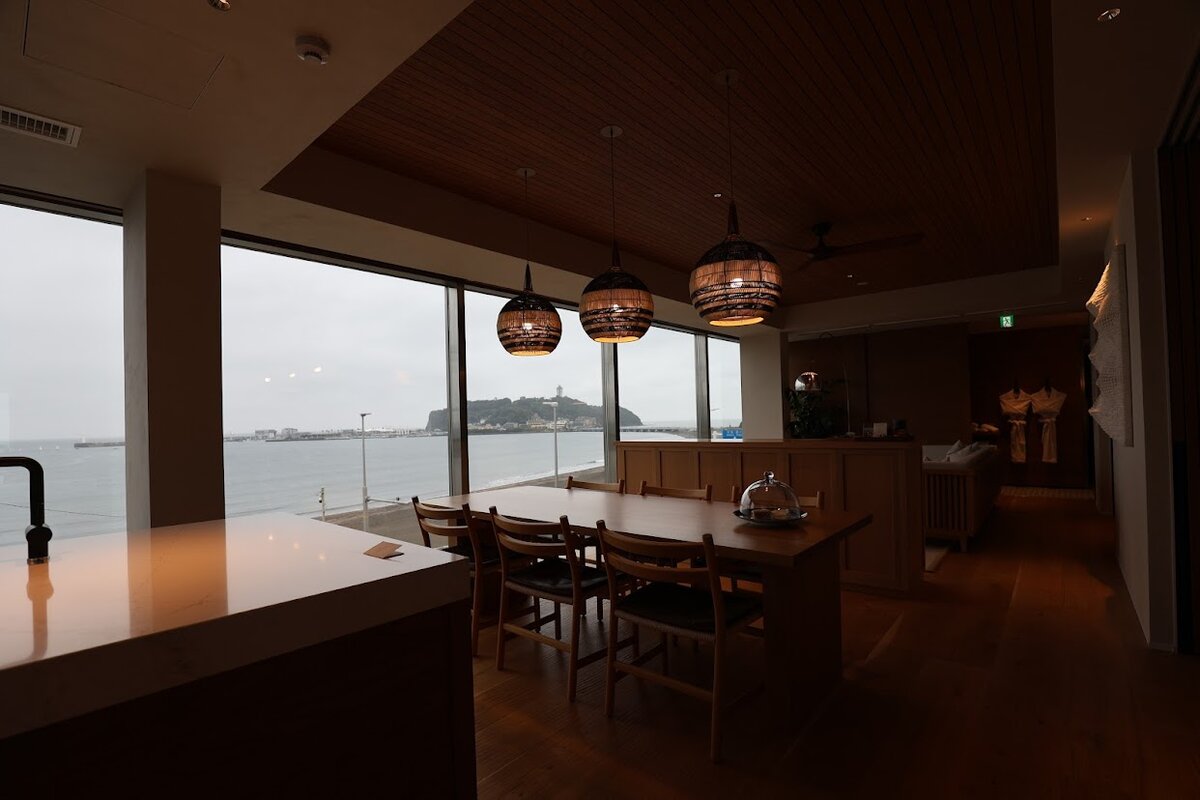 UMITO KAMAKURA KOSHIGOE：ホテルの部屋の内装、ダイニングテーブルとベッドルームが見える