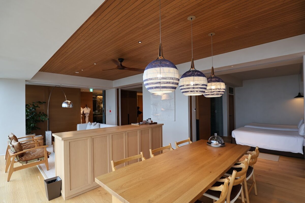 UMITO KAMAKURA KOSHIGOE：ホテルの内装。ダイニングテーブルとベッドルームが見える。