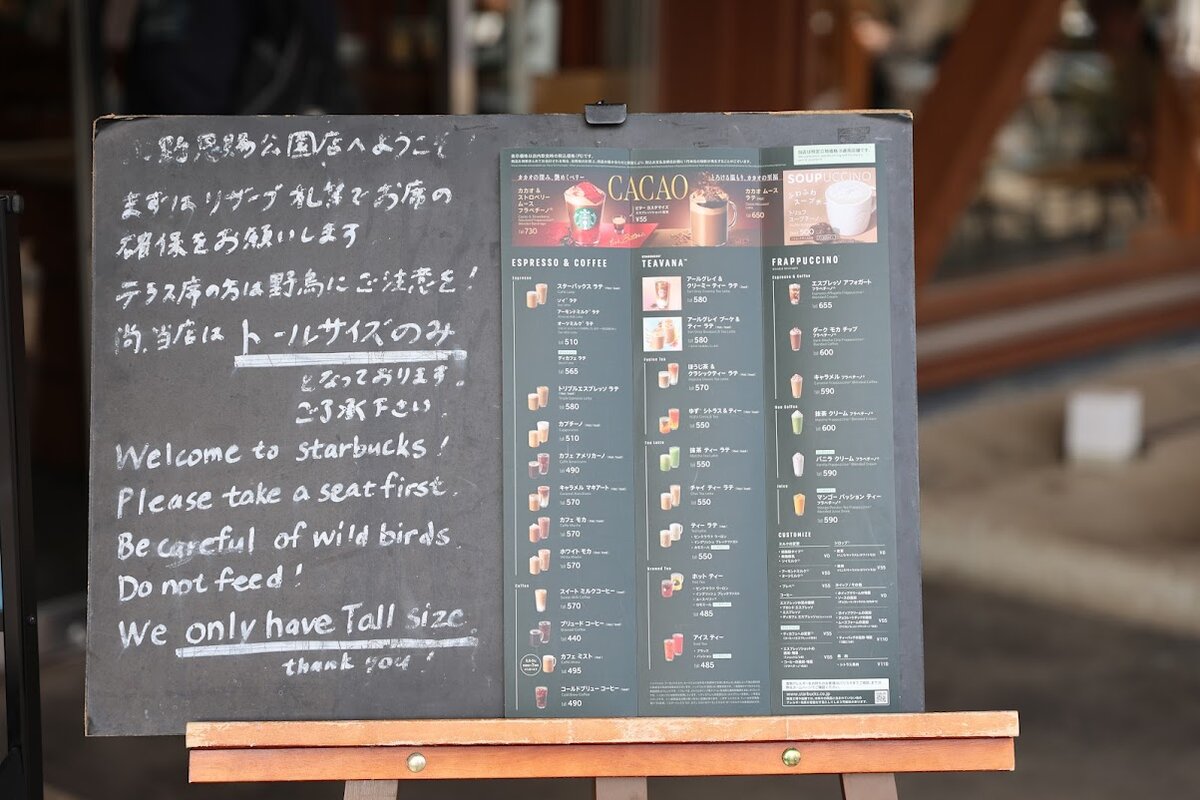 スターバックスコーヒー上野恩賜公園店：スターバックスコーヒーの店舗外観。周囲には木々や花壇がある。