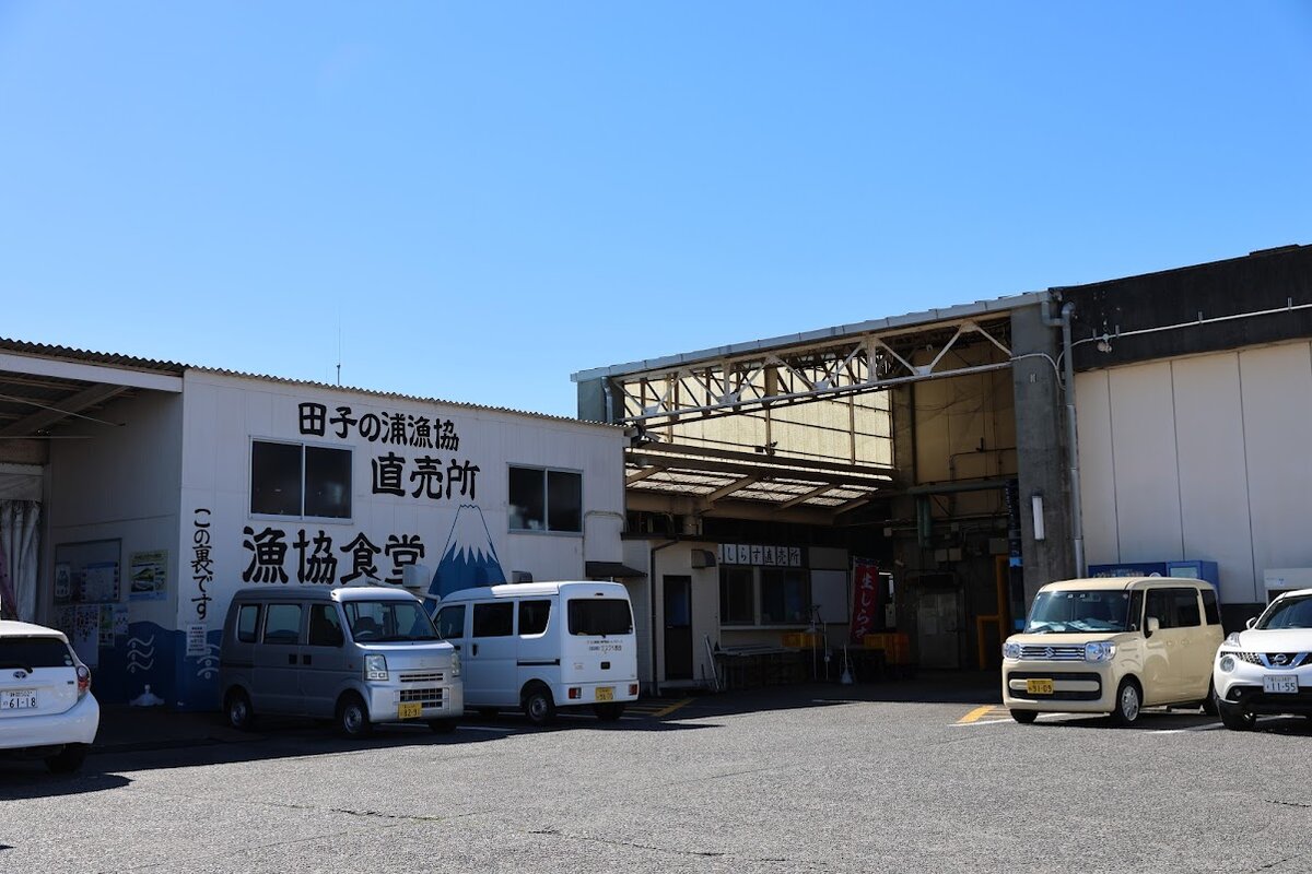 田子の浦漁協食堂：富士山を背景にした漁港の風景。漁協食堂の看板が見える。